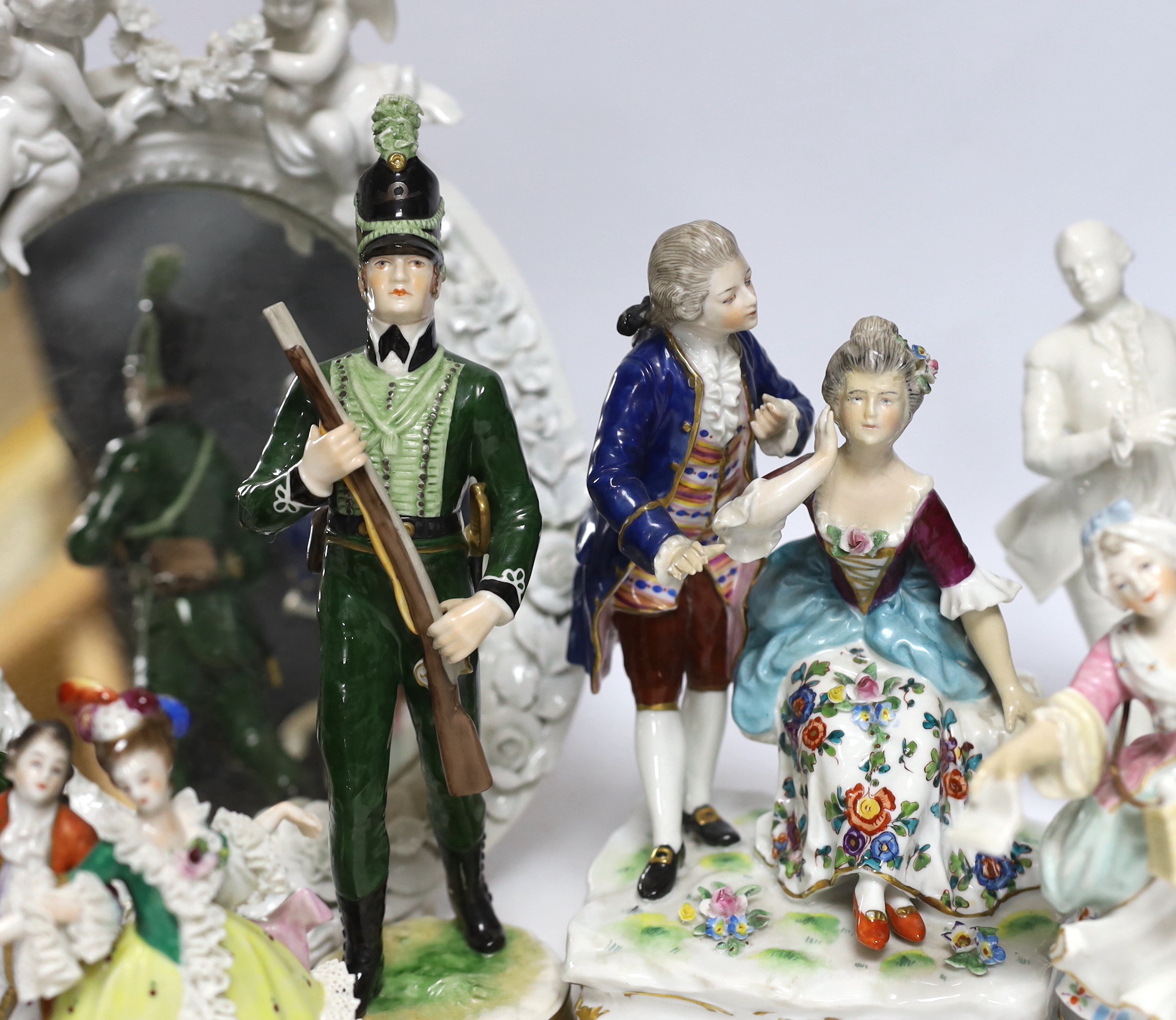 Seven Continental porcelain figures and an oval mirror with floral encrusted decoration, 27cm high